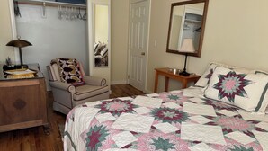 A bedroom with a bed, a chair, a dresser, a mirror, and a closet.
