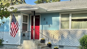 A two-story house with a red door, a blue exterior, and an American flag.