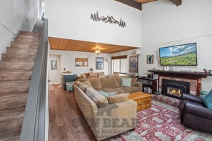 A spacious living area with a fireplace, a sofa set, a coffee table, and a television.
