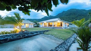A two-story house with a covered patio, surrounded by a stone wall and a small water feature. - Villa Kahia by Tahiti Homes (Windward Islands)