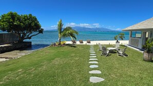 A well-maintained lawn with a stone pathway leading to outdoor seating by the ocean. - Villa Kahia by Tahiti Homes (Windward Islands)