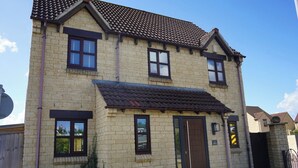 A two-story house with a tiled roof, brick walls, and a front door. - Atworth Haven: 4-Bed Home with Garden (Atworth)
