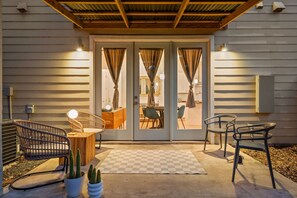 A patio with two rocking chairs, a wooden table, and a checkered rug. - East Austin 3BR • Sleeps 8 • Free Parking • ACL + F1 (Austin)