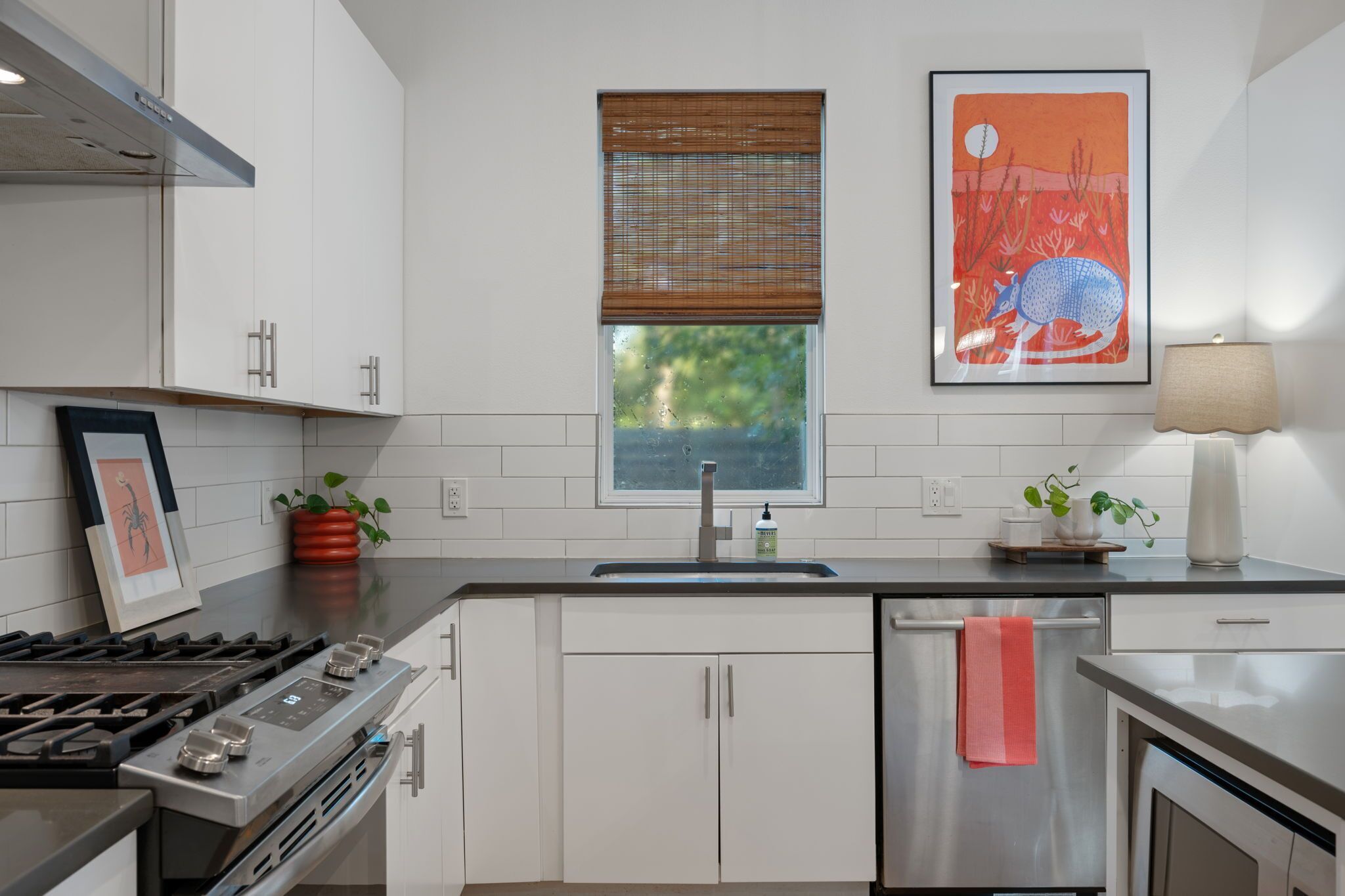 Una cucina moderna con mobili bianchi, un lavello in acciaio inossidabile e una cucina a gas.