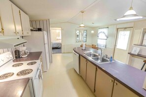 A compact kitchen with a stove, sink, and a dining area.