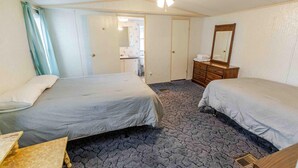 Een slaapkamer met twee bedden, een dressoir, een spiegel en een plafondventilator.