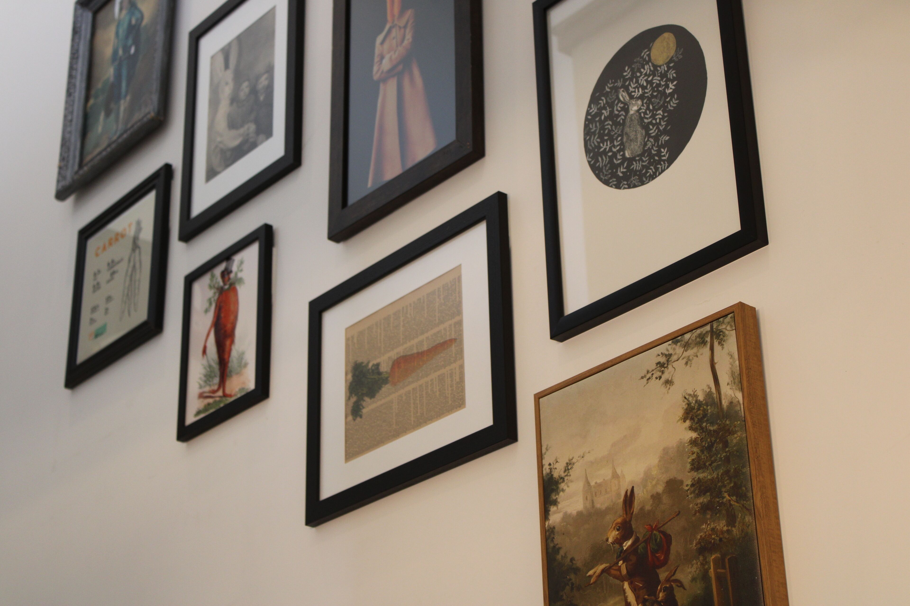 Pared con varios cuadros enmarcados de diferentes tamaños y estilos.