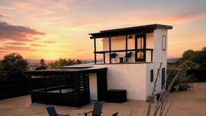 Uma casa moderna com um pátio, área de estar externa e vista para o pôr do sol.