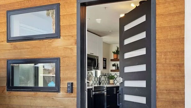 A modern kitchen with black cabinets, a microwave, and a tiled backsplash.