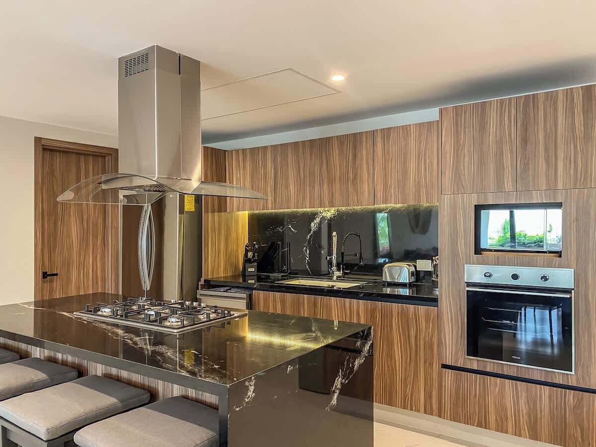 A modern kitchen with a central island, built-in oven, and a TV mounted on the wall.