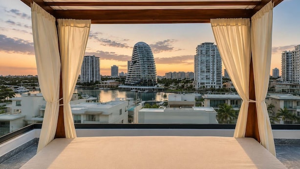 Un balcon offrant une vue sur le paysage urbain, avec des bâtiments modernes et une étendue d’eau.