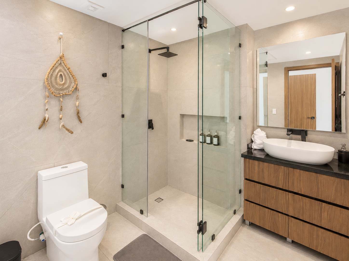 A modern bathroom with a glass-enclosed shower, a white toilet, and a wooden vanity with a sink.