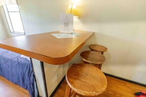 A corner of a room with a wooden table and two stools.