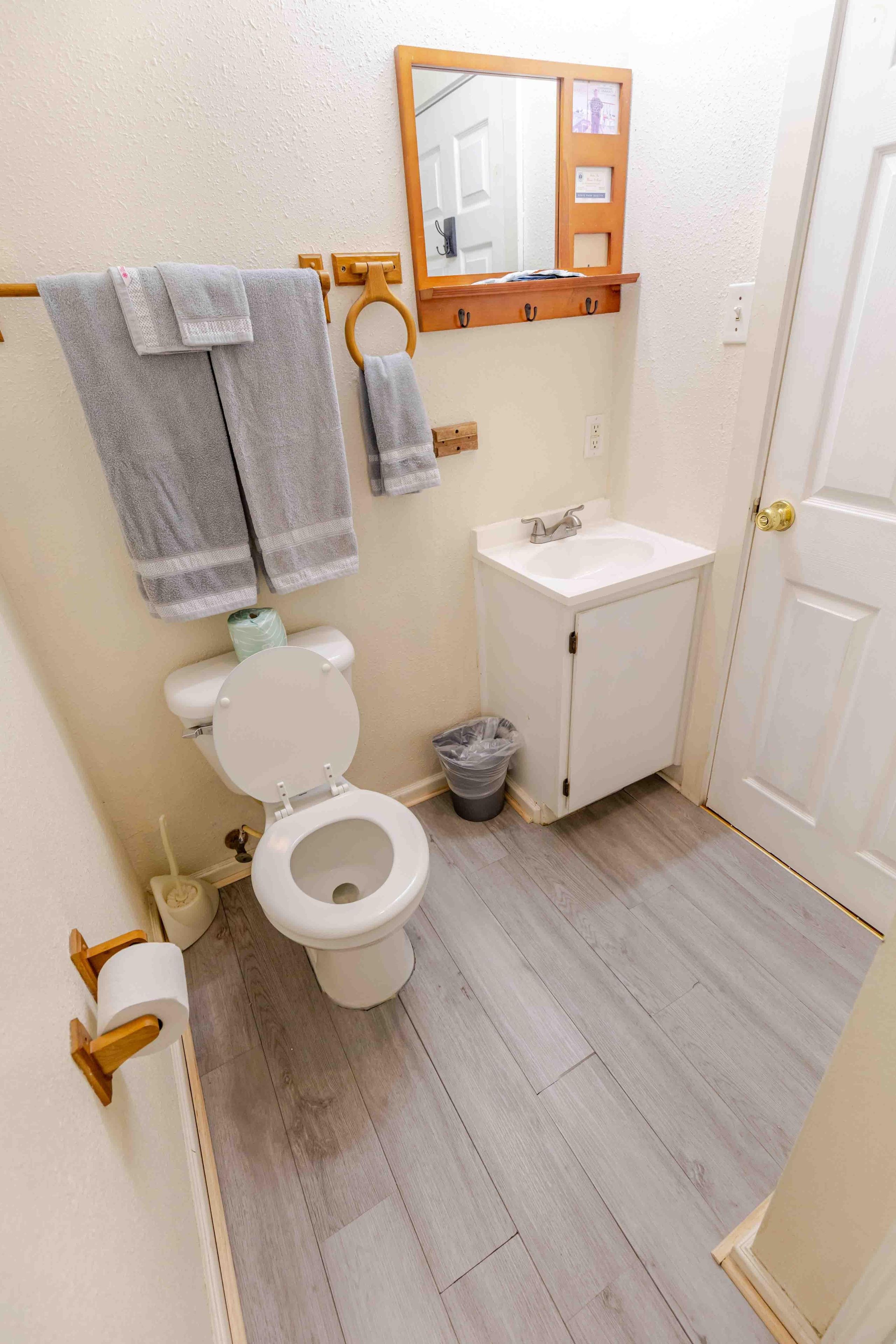 A bathroom with a toilet, sink, and wooden towel rack.