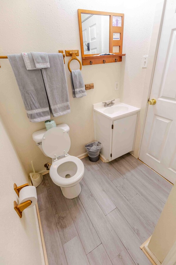 A bathroom with a toilet, sink, and wooden towel rack.