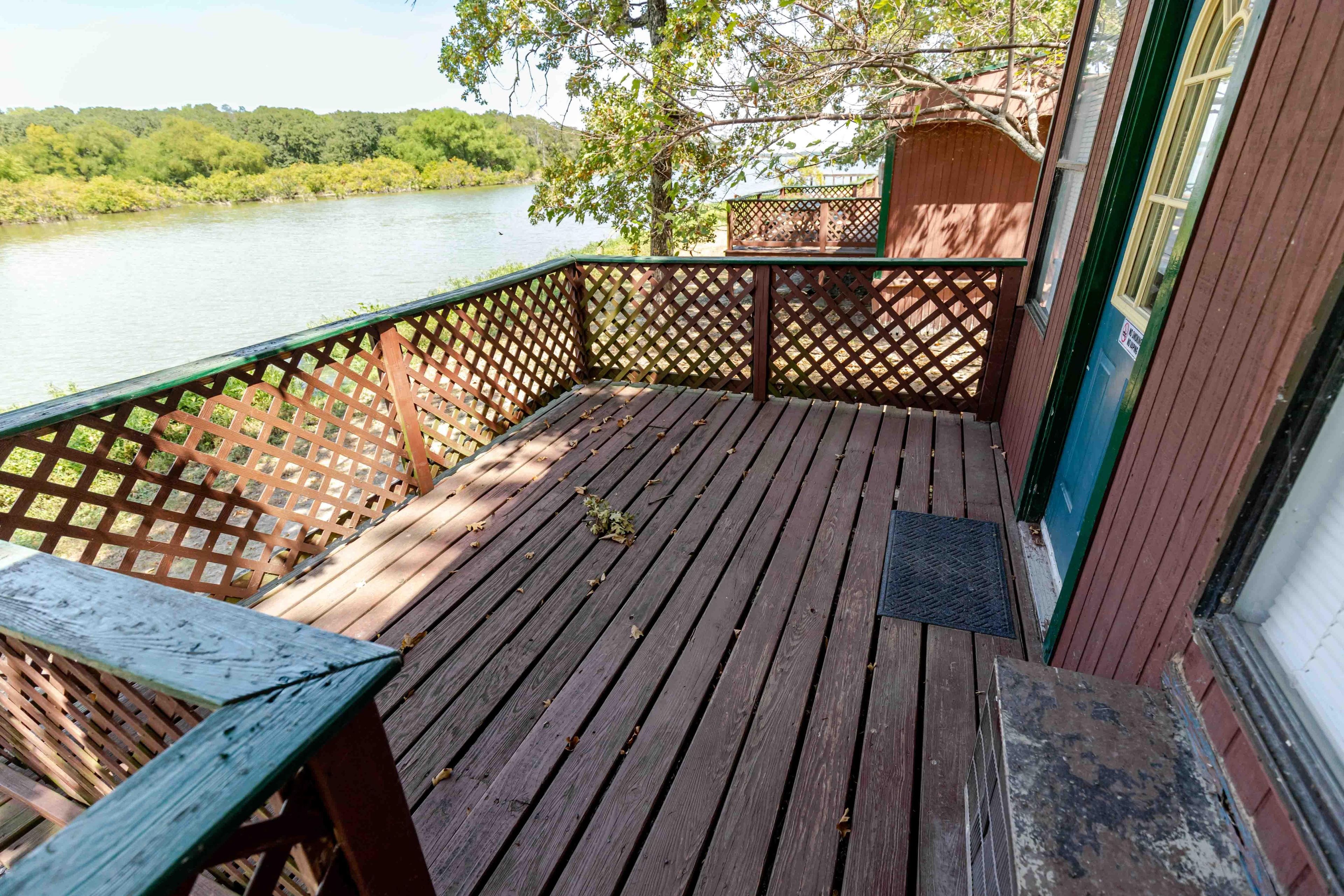 A wooden deck with a view of a river and a small structure in the background.