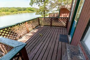 A wooden deck with a view of a river and a small structure in the background.