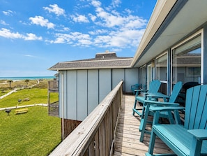 A balcony with a view of the beach, wooden deck, and outdoor seating. - Shared Heated Pool, Boardwalk to Beach, Golf Cart Access (Port Aransas)