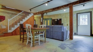 A dining area with a wooden table and chairs, a staircase, and a grey sofa. - Toad Hall Carriage House-quaint family friendly home on a historic estate (Fly Creek)