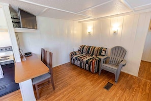 Un espacio habitable compacto con kitchenette, un sofá, una silla y una mesita.