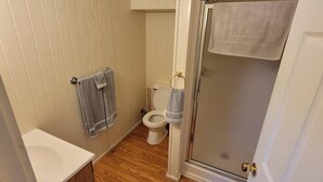 A small bathroom with a toilet, a shower, and a sink.