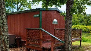 A red wooden structure labeled 'STATE RM' with a wooden staircase leading to a platform, surrounded by trees and a body of water.