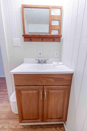 Un baño con tocador de madera, espejo y lavabo blanco.