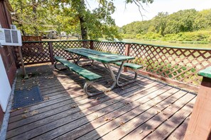 Terraza de madera con una mesa de picnic y bancos, rodeada por un cerramiento de celosía.