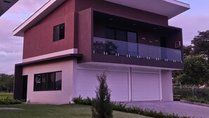Una casa moderna de dos pisos con techo plano, ventanas amplias y un garaje.