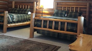 A log cabin room with two wooden beds, a window, a lamp, and a rug. - Marvelous 1-bedroom cabin “Moose”in Ririe (Rigby)