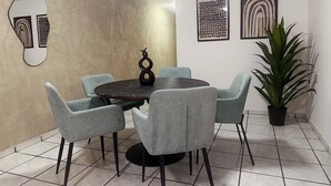 A dining area with a round table, four grey chairs, a potted plant, and three framed artworks on the wall. - Casa Privada 3 Hab 6p Plaza de Toros Centro (Guadalajara)