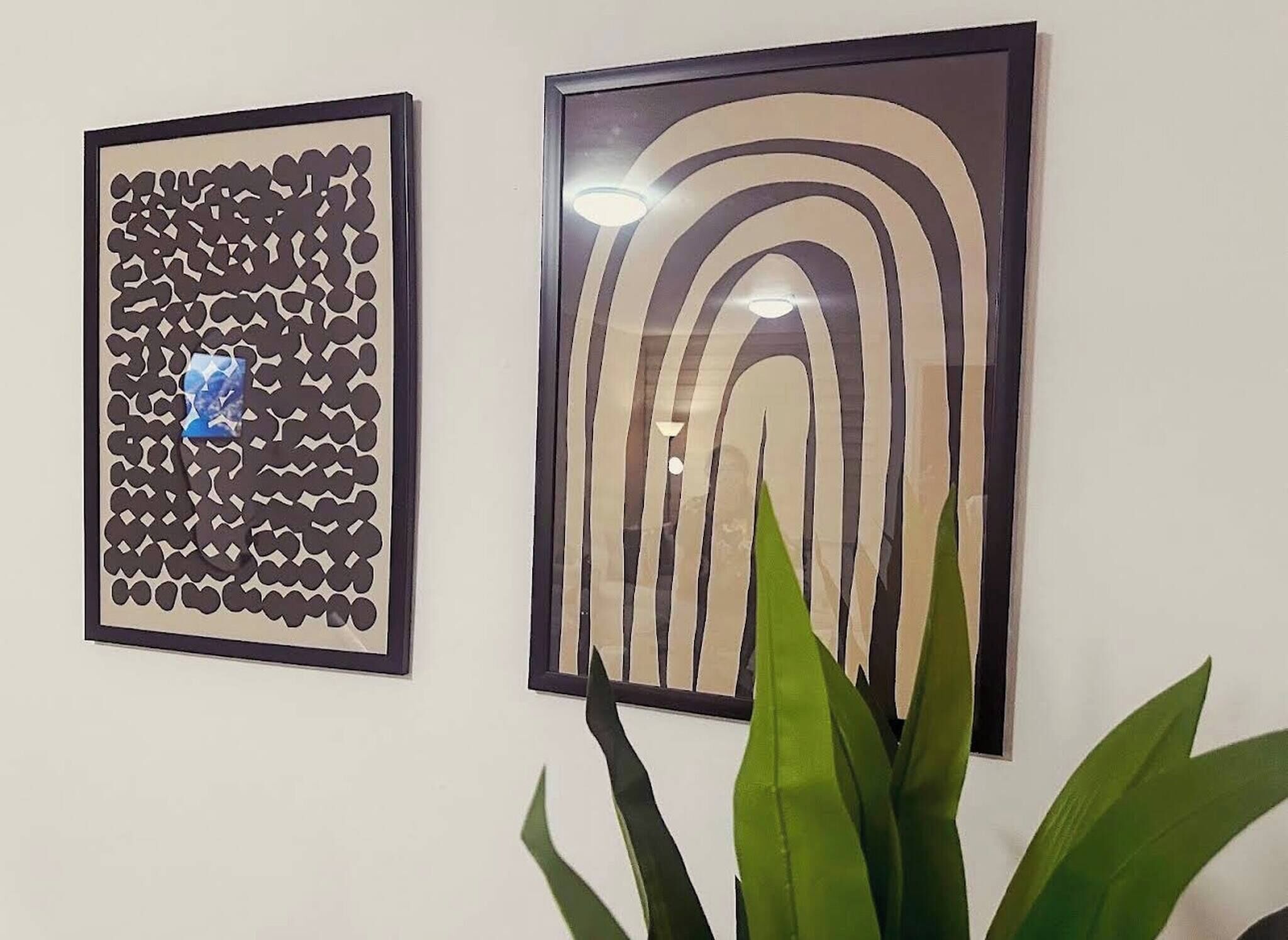 Deux œuvres d’art encadrées sont accrochées au mur : l’une présente un motif de formes irrégulières, et l’autre, des arcs concentriques.