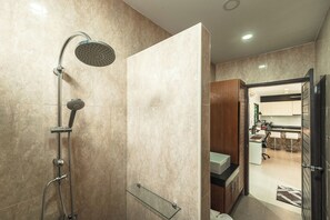 Ein modernes Badezimmer mit Dusche, einer Glasablage und Blick in einen Küchenbereich.