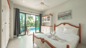 A bedroom with a large bed, a ceiling fan, a view of a swimming pool, and a painting on the wall. - 4Br Near Pier Private Pool & Garden V246 (Rawai)