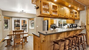 A kitchen with wooden cabinets, a central island with stools, a refrigerator, and a coffee maker.