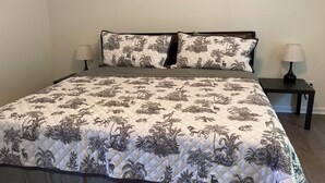 A bed with a quilted cover featuring a nature pattern, flanked by two nightstands with lamps. - Peaceful & Spacious Family Home (Savannah)