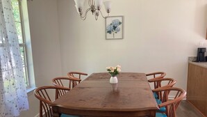 A dining room with a wooden table, six chairs, a vase with flowers, a chandelier, and a framed picture on the wall. - Peaceful & Spacious Family Home (Savannah)