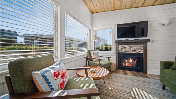 A modern living room with a fireplace, large windows, and comfortable seating. - Cozy Cottage Steps from Beach (Pacific Beach)