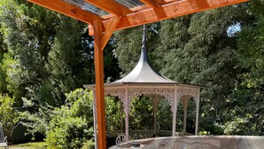 Una bañera de hidromasaje de madera en un jardín, con el rótulo 'alpine spas'.