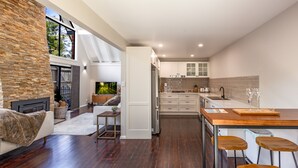 Una cocina moderna con armarios blancos, una isla de madera y un comedor con taburetes de bar.