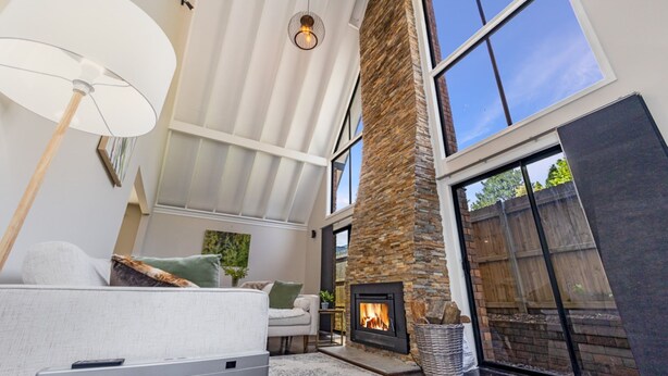 Amplia sala de estar con chimenea, ventanas grandes y un techo alto.