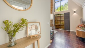 Un interior moderno con una consola de madera, un mapa enmarcado y un florero con flores.