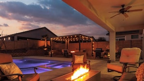 Eine Terrassenanlage im Freien mit Pool, Feuerstelle und Sitzgelegenheit.