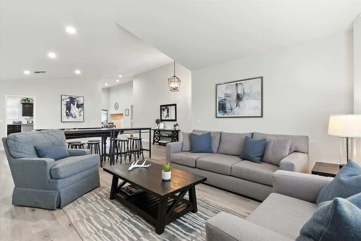 Ein modernes Wohnzimmer mit einer Couch, Sesseln, einem Couchtisch und einem Essbereich mit Stühlen und einem Tisch.