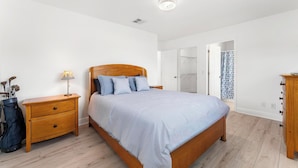 Een slaapkamer met een houten bed, nachtkastje, lamp en een kledingkast.