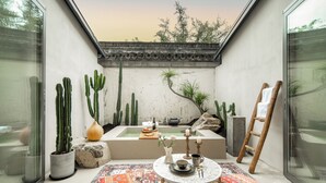 A spa area with a hot tub, cacti, a ladder, and a patterned rug. - Jiangnanfu Bed and Breakfast (Huzhou)