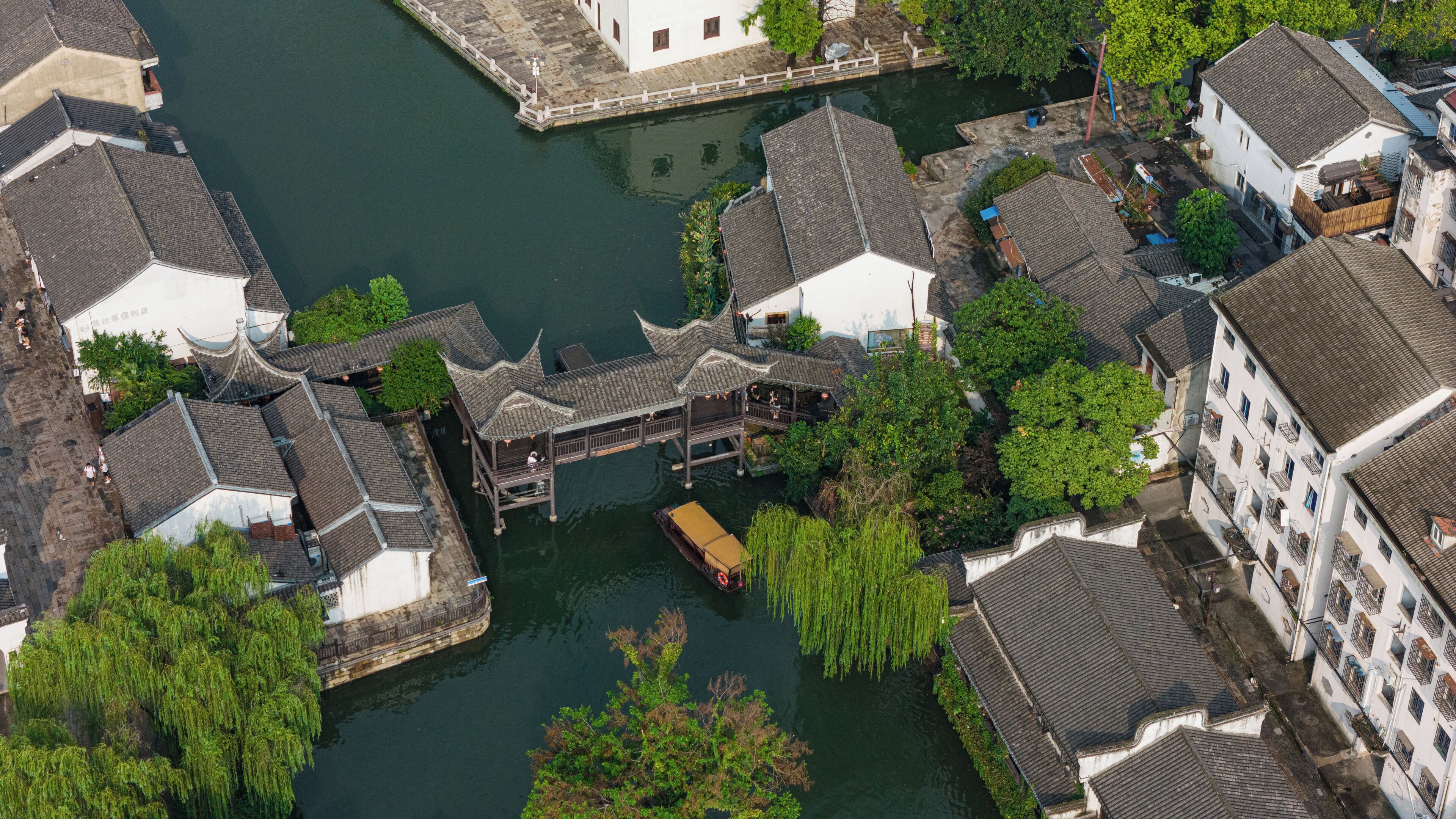 An aerial view of a traditional Chinese courtyard with a wooden pavilion, surrounded by buildings with tiled roofs.