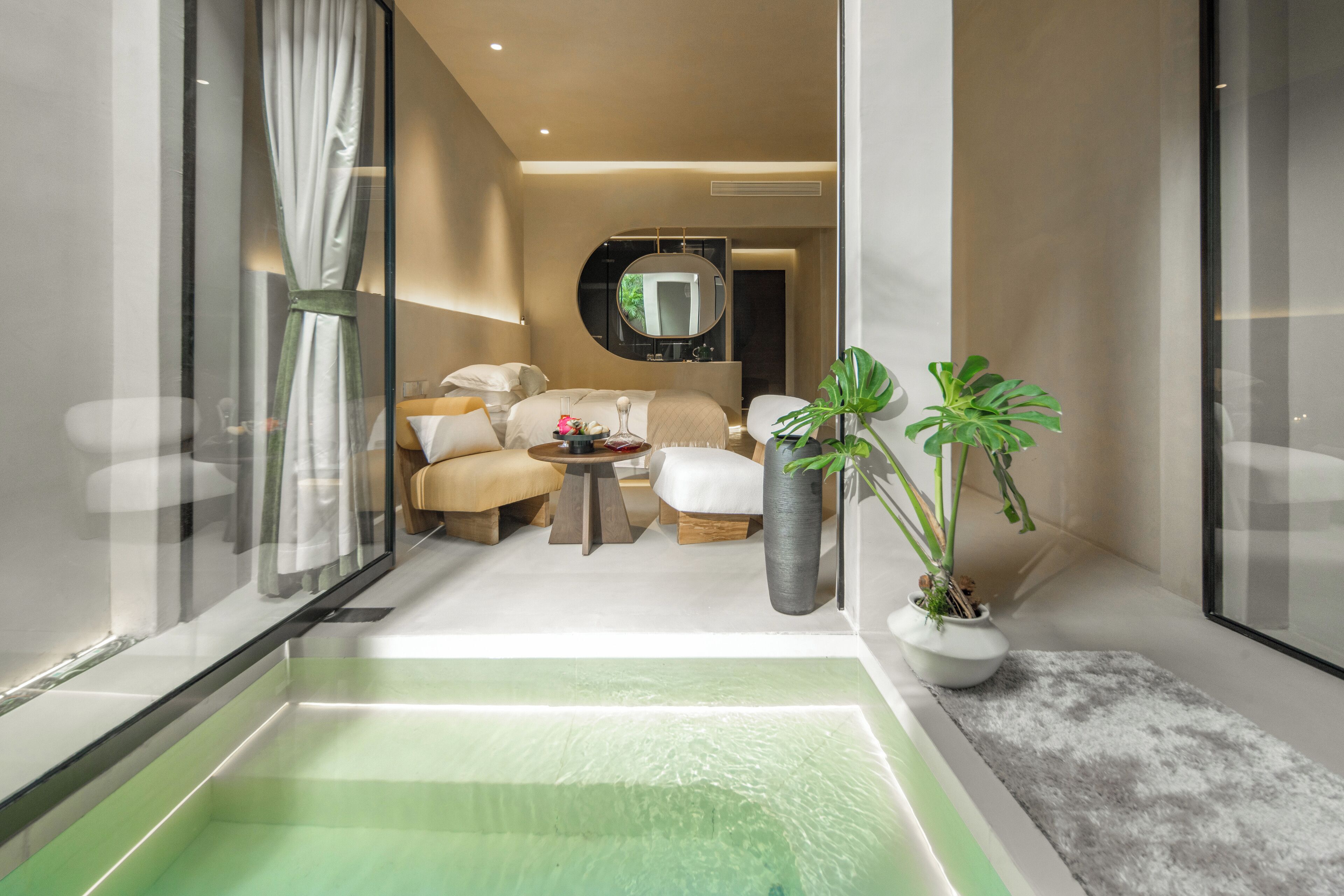A modern bathroom with a glass-enclosed jacuzzi, a large mirror, and a potted plant.