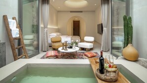 A modern room with a glass wall, a bathtub, and a dining area with a table set for two. - Jiangnanfu Bed and Breakfast (Huzhou)