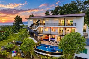Una casa de varios pisos con piscina, balcones y una escalera.